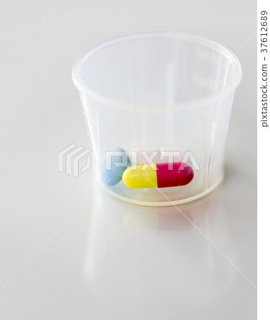 close up of pills and capsule in medicine cup 37612689
