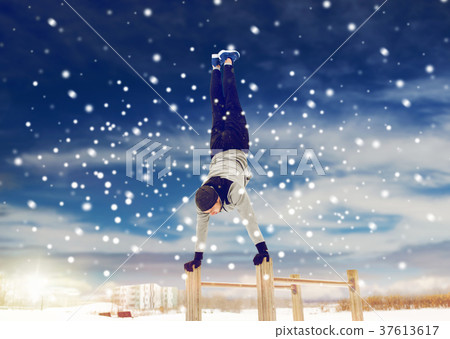 young man exercising on parallel bars in winter 37613617