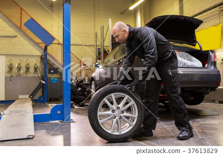 auto mechanic changing car tire at workshop 37613829