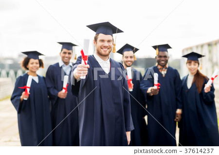 happy students in mortar boards with diplomas 37614237