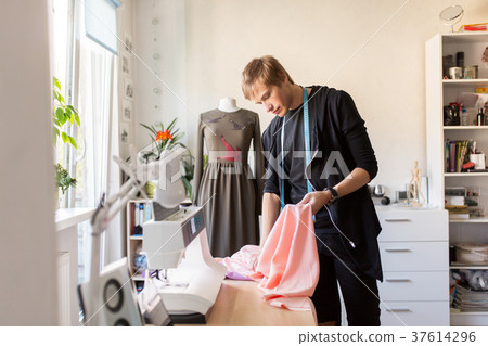 fashion designer with cloth making dress at studio 37614296