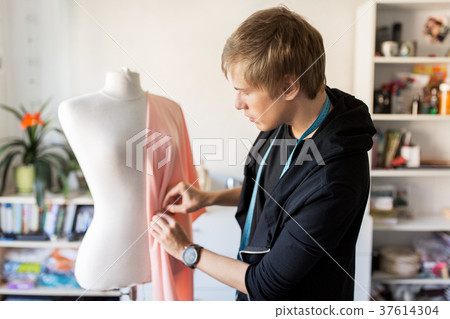 fashion designer with dummy making dress at studio 37614304