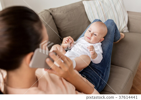 mother with baby calling on smartphone at home 37614441