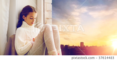 sad girl sitting on sill at home window 37614483