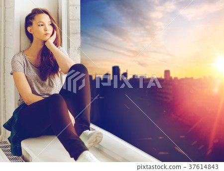 sad pretty teenage girl sitting on windowsill 37614843