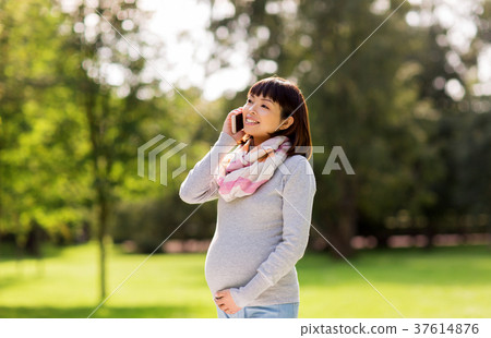 pregnant asian woman calling on smartphone at park 37614876