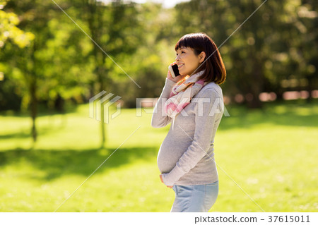 pregnant asian woman calling on smartphone at park pregnant asian woman calling on smartphone at park 37615011