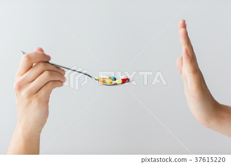 close up of female hand holding spoon with pills 37615220