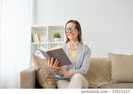 happy woman in glasses reading book at home 37615257