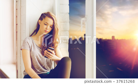 sad pretty teenage girl with smartphone texting 37615268