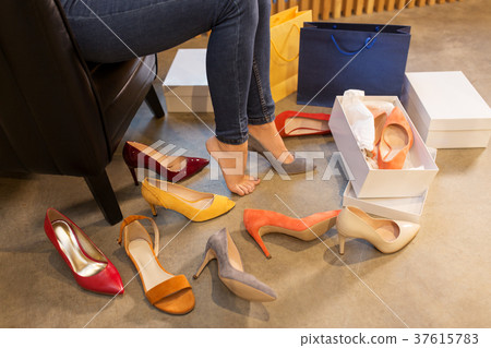 young woman trying and choosing shoes at store 37615783