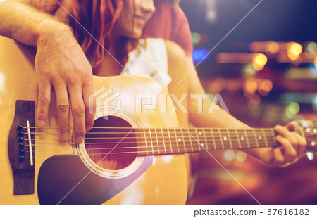 close up of couple with guitar over night lights 37616182