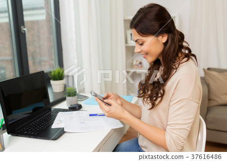 woman with papers and smartphone working at home 37616486