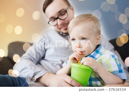 father and son drinking from cup at home father and son drinking from cup at home 37616534
