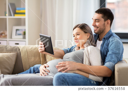 man and pregnant woman with tablet pc at home man and pregnant woman with tablet pc at home 37616558