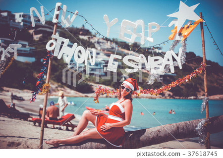 Cute woman in red dress, sunglasses and santa hat 37618745