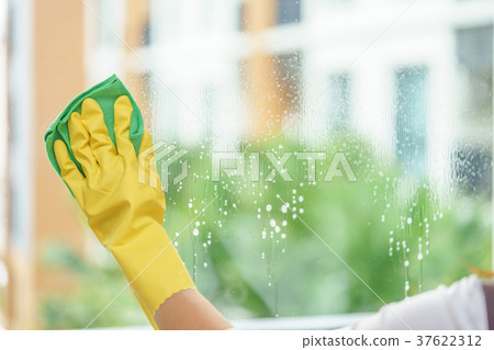 Woman housekeeper cleaning the mirror with cloth. Woman housekeeper cleaning the mirror with cloth. 37622312