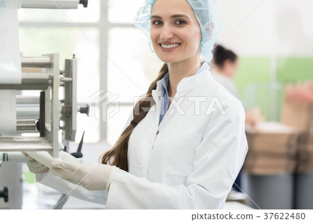 Happy employee wearing lab coat while handling 37622480