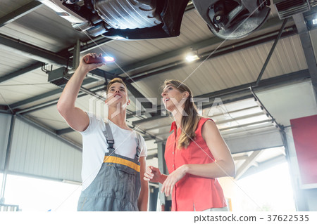 Reliable auto mechanic checking the car of a woman 37622535