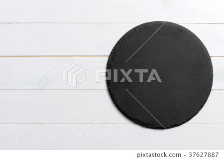 Round slate stand board a wooden background.  37627887