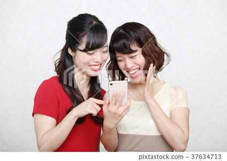 Two young women wearing smartphones and one piece 37634713