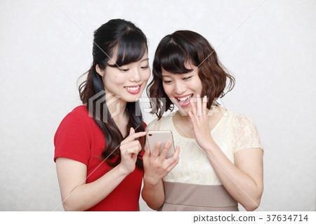 兩個年輕女人穿著智能手機和一件 37634714