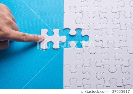 Hand holding piece of white puzzle Hand holding piece of white puzzle 37635917