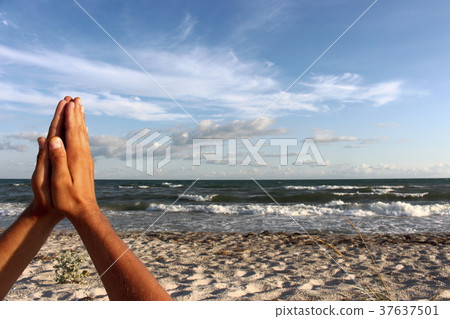 Pray hands against sea and blue sky. 37637501