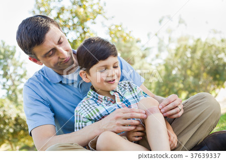 Loving Father Puts a Bandage on the Elbow of His Young Son in th 37639337