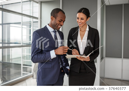 Cheerful man and woman are standing in office with 37640377