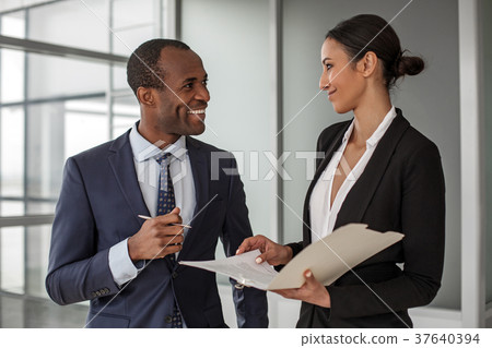 Positive colleagues are standing with documents Positive colleagues are standing with documents 37640394