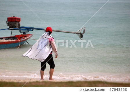 Tourists with raincoat or Life jacket on the beach 37643368
