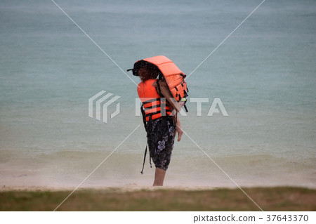 Tourists with raincoat or Life jacket on the beach 37643370