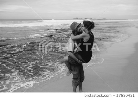 a guy and a girl are kissing on a beach 37650451