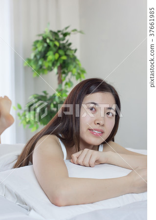 Young woman operating a smartphone with a bed Young woman operating a smartphone with a bed 37661985