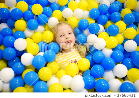 Happy little girl having fun in ball pit in kids indoor play center 37666431