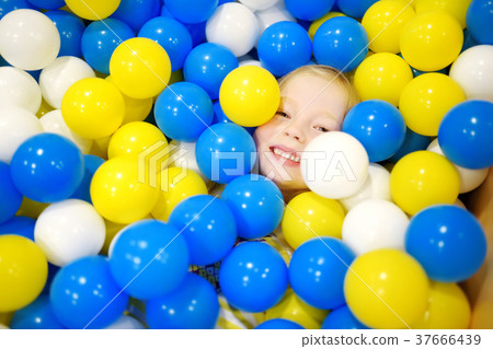Happy little girl having fun in ball pit in kids indoor play center 37666439