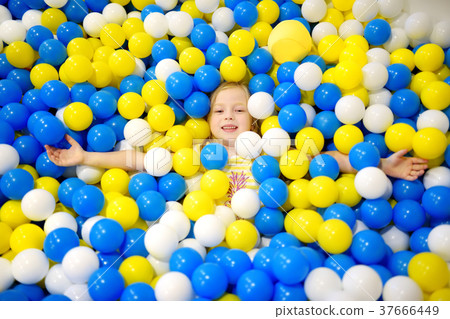 Happy little girl having fun in ball pit in kids indoor play center Happy little girl having fun in ball pit in kids indoor play center 37666449