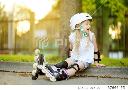Pretty little girl learning to roller skate on beautiful summer day in a park 37666455
