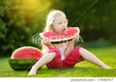 Funny little girl biting a slice of watermelon outdoors on warm and sunny summer day 37666457