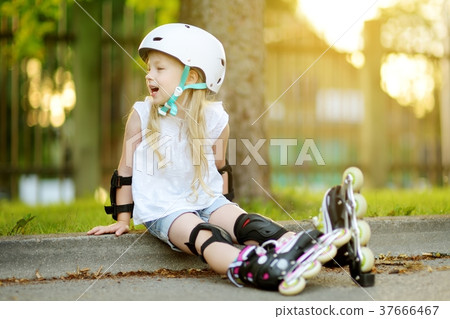 Pretty little girl learning to roller skate on beautiful summer day in a park 37666467