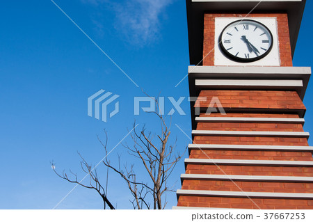 red brick block clock tower in blue sky background 37667253