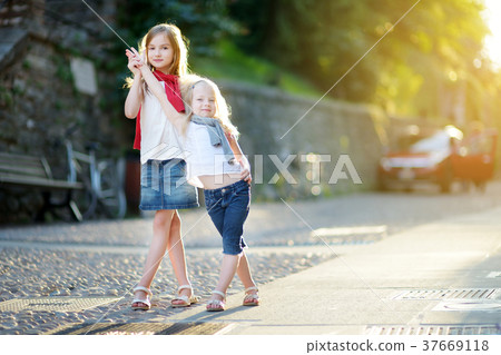 Two adorable little sisters having fun on warm and sunny summer evening in Desenzano del Garda 37669118