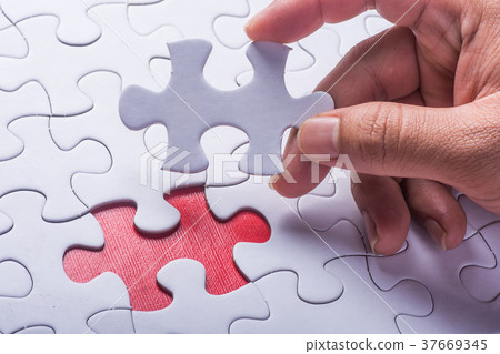 Hand holding piece of blank jigsaw puzzle Hand holding piece of blank jigsaw puzzle 37669345