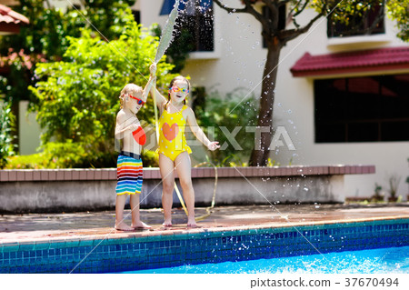 Kids play with water hose at swimming pool. 37670494