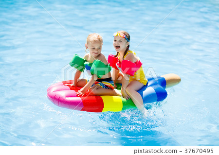 Kids on inflatable float in swimming pool. 37670495