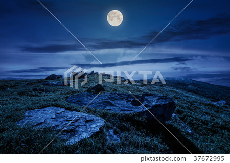 rocky formation on grassy hillside at night 37672995