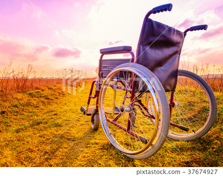 Empty wheelchair on the meadow at sunset 37674927