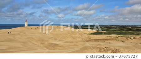 Lighthouse slowly disappearing under asand dune. 37675727