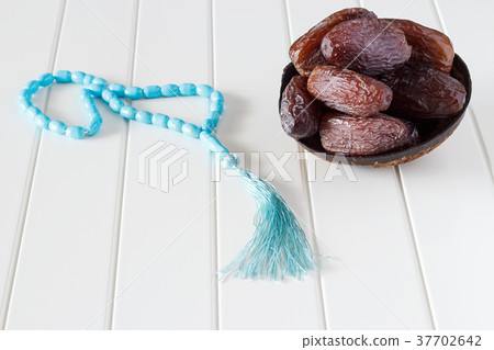 Fresh dates Medjool in coconut bowl and rosary. Fresh dates Medjool in coconut bowl and rosary. 37702642